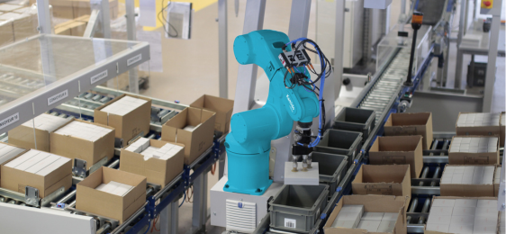 Robot industriel bleu effectuant une opération de picking automatisé sur une ligne de production avec des cartons.
